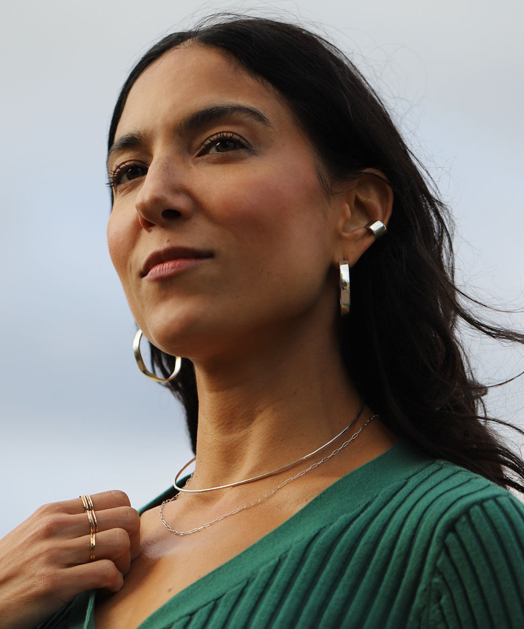 girl with bright silver jewelry wearing green sweater
