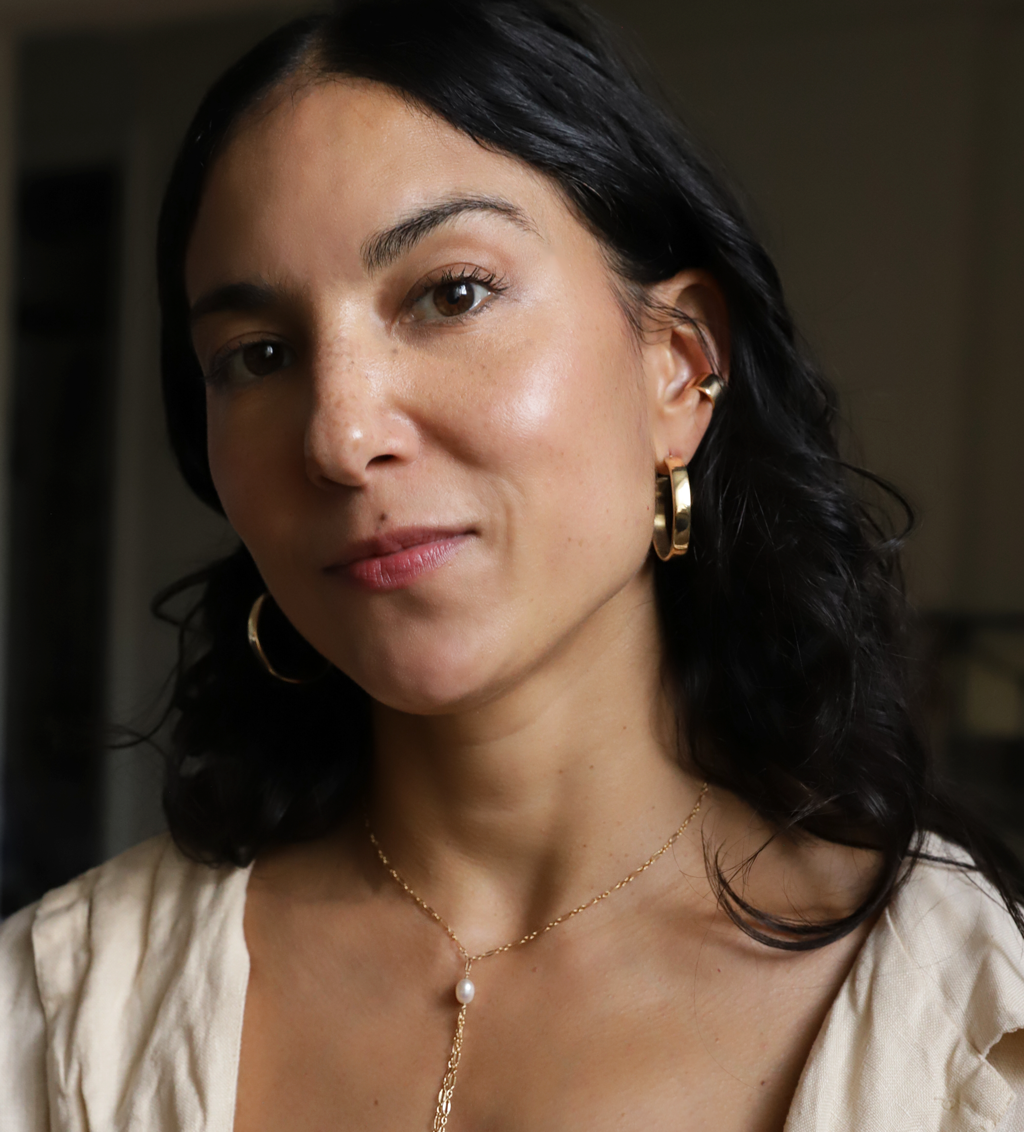 girl with black hair gold hoops and single pearl necklace