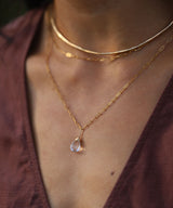 closeup of neck with delicate gold chain and quartz pendant necklace with gold wire choker