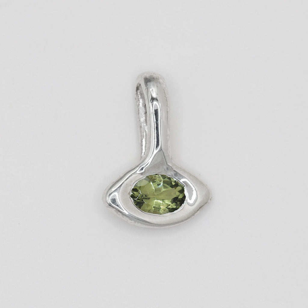 A sterling silver pendant featuring an organic, abstract teardrop-shaped setting with a faceted olive green tourmaline gemstone in the center, set against a plain light gray background.