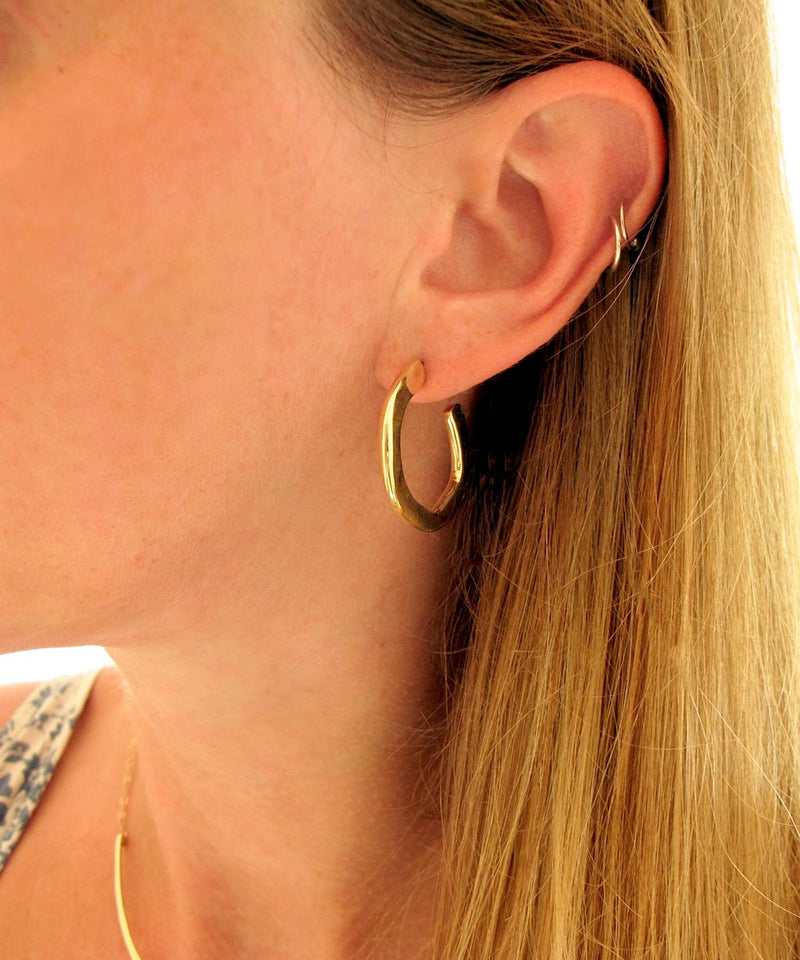 photo of ear with medium 1.5 inch gold hoop earring on an ear