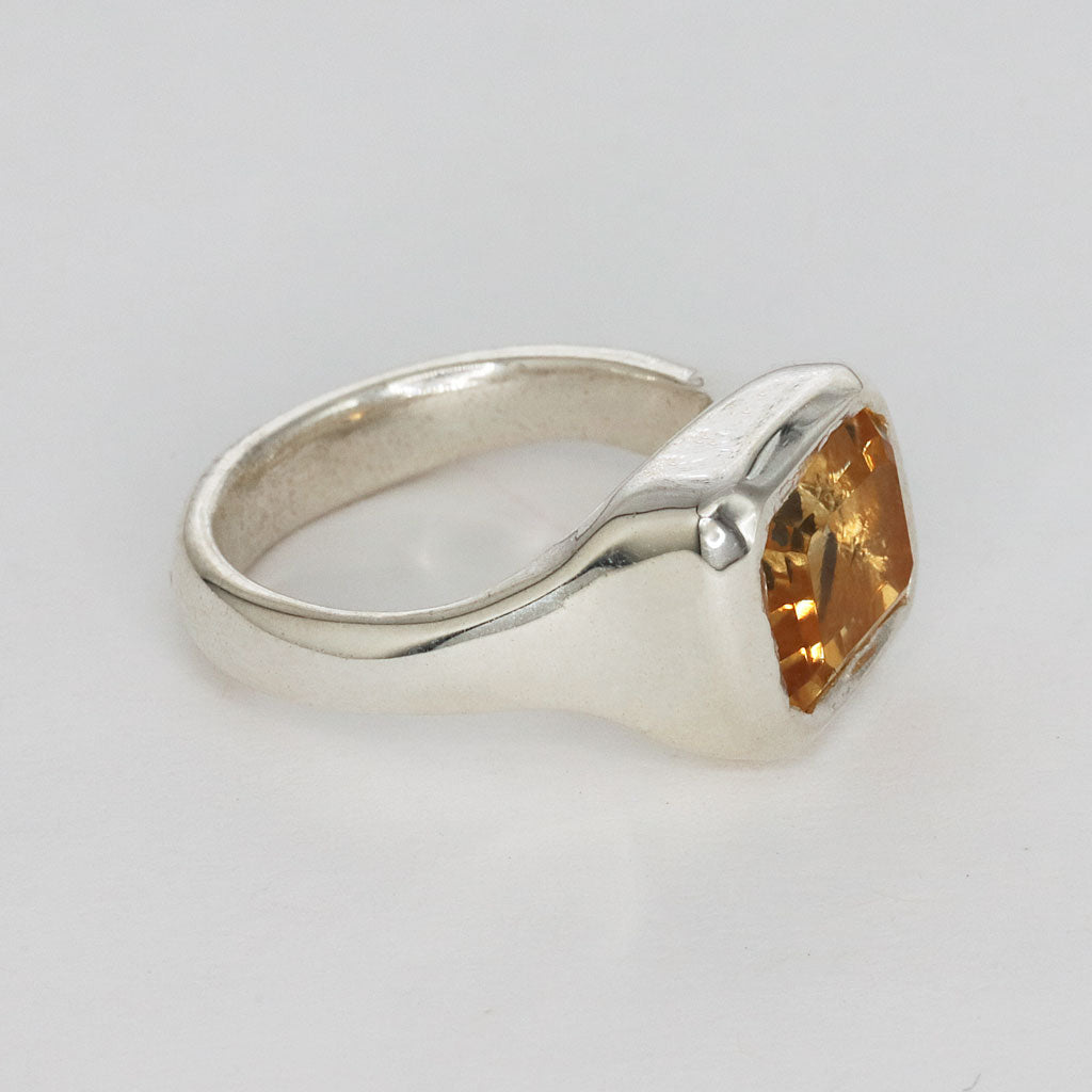 side view of a golden yellow citrine and sterling silver ring on light gray background