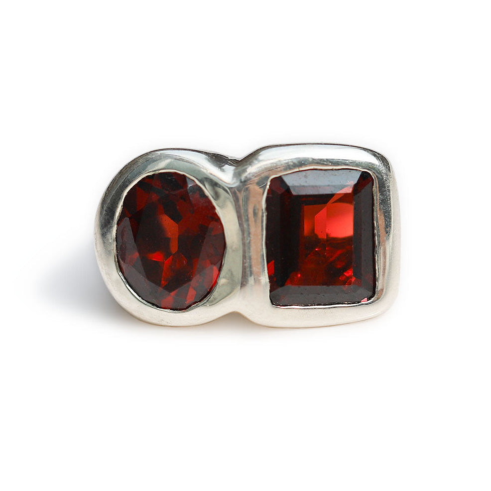 A silver-toned double-stone ring featuring one oval-cut dark red gemstone and one rectangular-cut dark red gemstone, set against a plain white background.