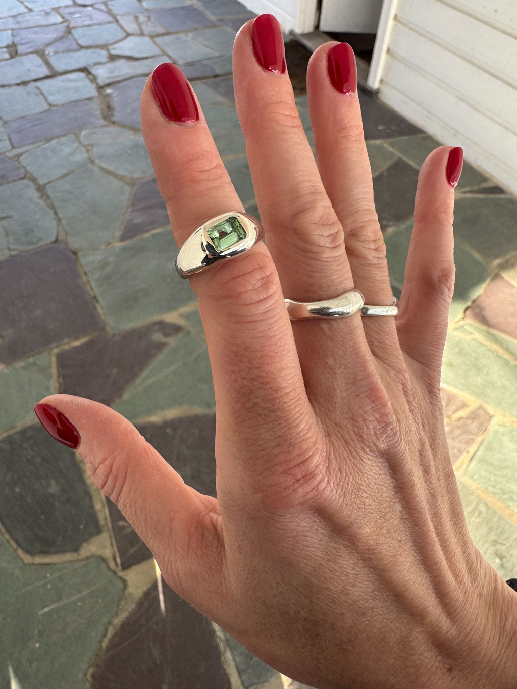 Hand with two silver rings on a stone pavement background