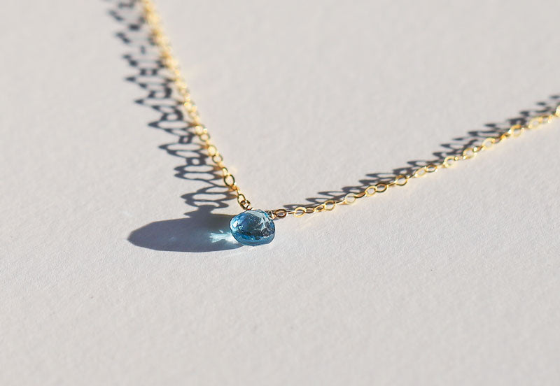 angled view of london blue topaz and gold chain pendant