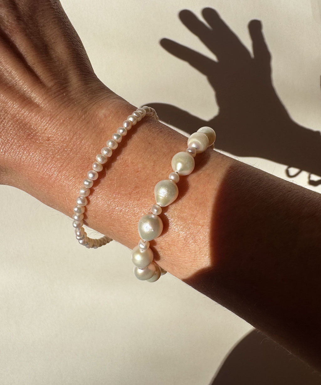 wrist with two different white freshwater pearl bracelets