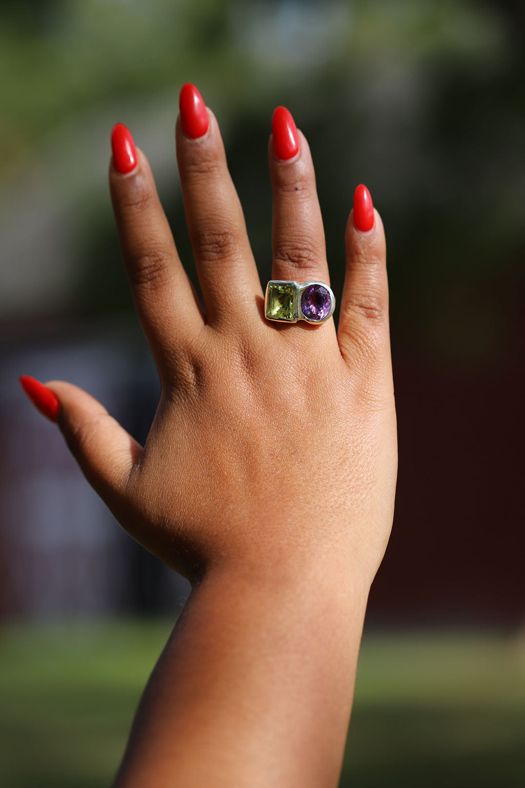 Hand wearing a ring with gemstones against a blurred background