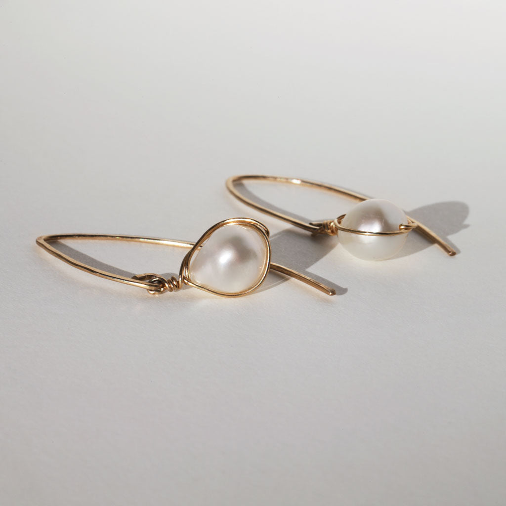 closeup side view of gold wire wrapped white pearl earrings