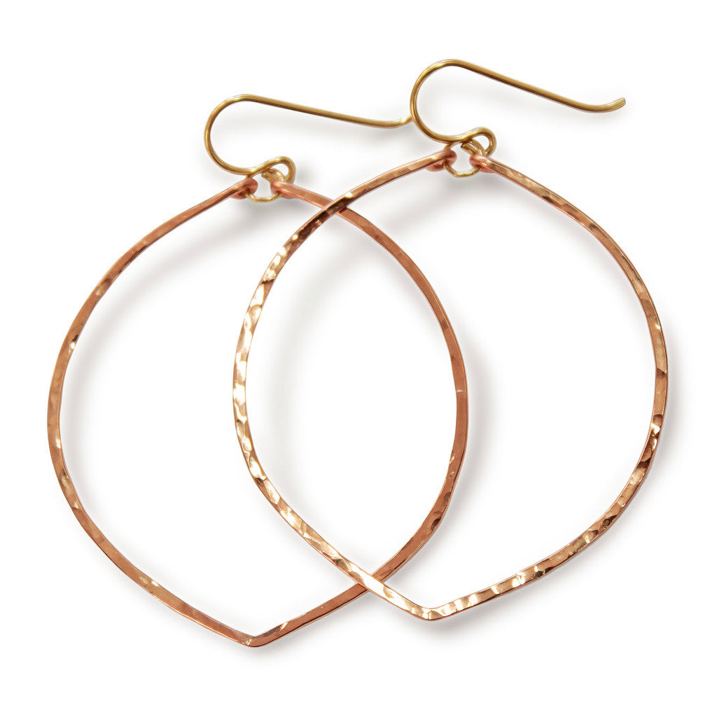 rose gold filled fig hoop earrings on a white surface partially reflecting light