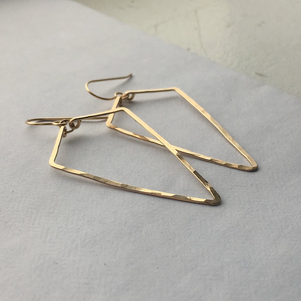 14k gold filled arrowhead hoop earrings laying on a grey surface