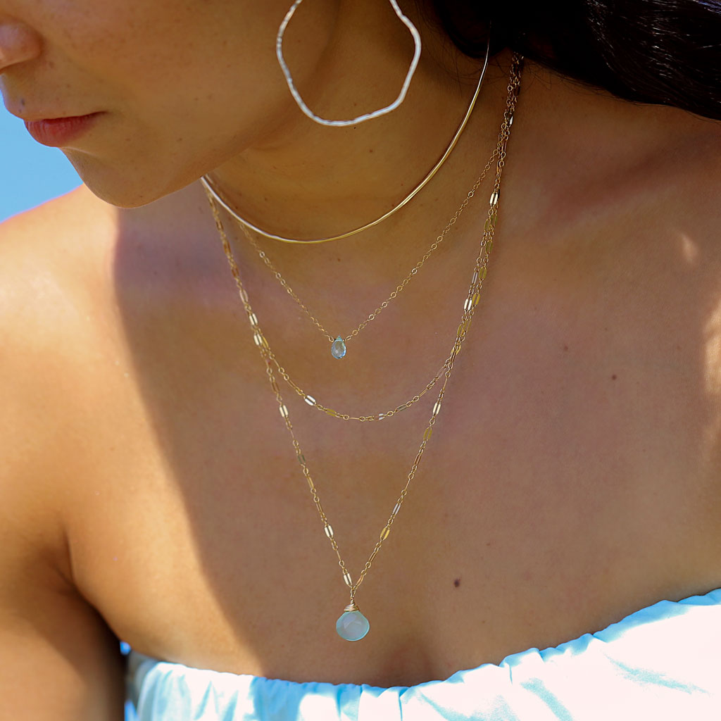 brunette on a blue top wearing a 14k gold filled halo collar under sunlight