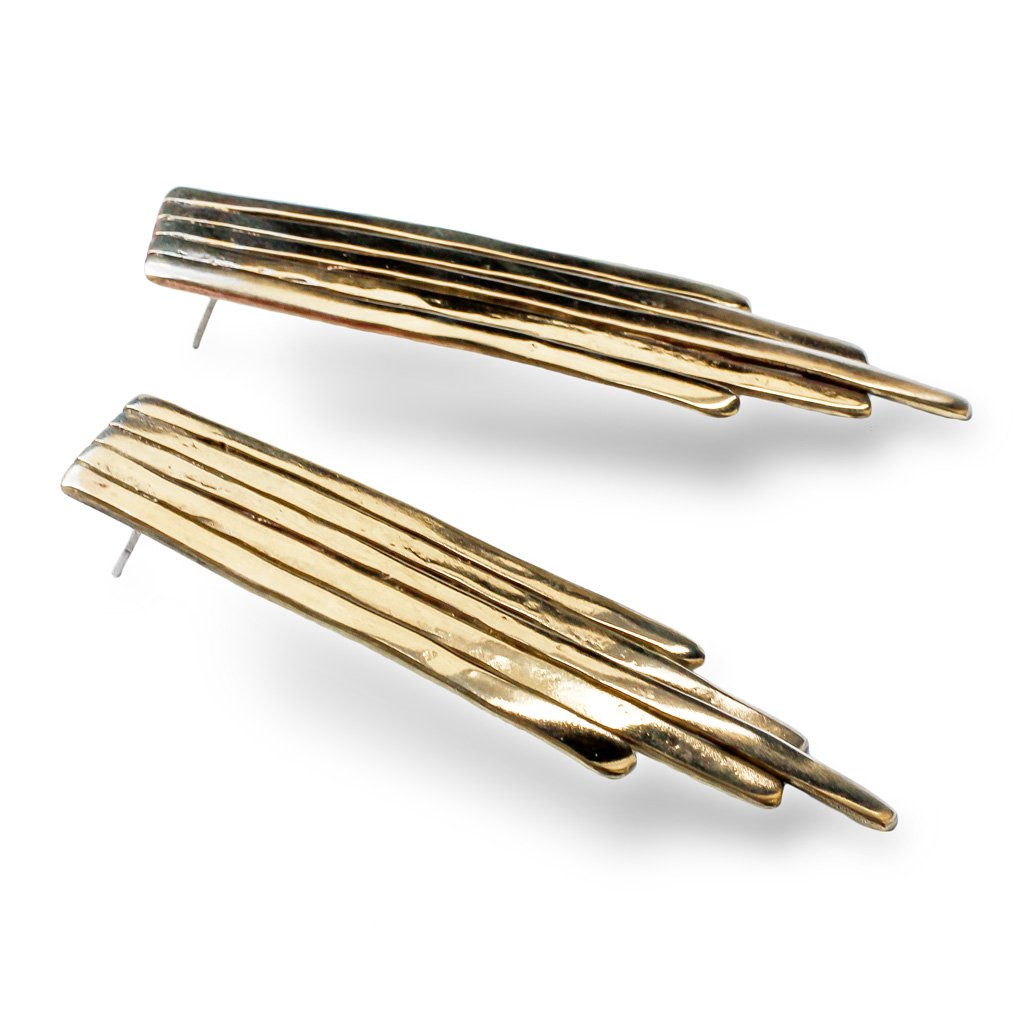 gold brass empire earrings laying on white surface under bright light