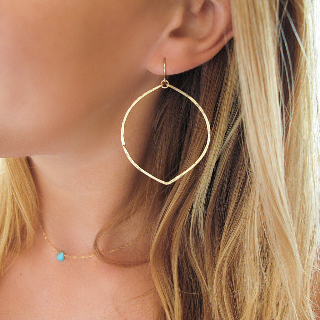 blond woman wearing 14k gold filled fig hoop earrings