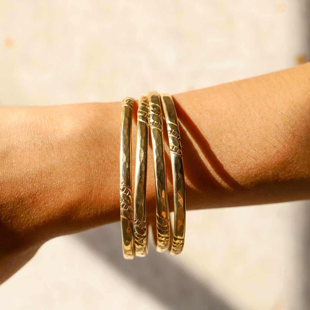 woman wrist close up wearing set of four florie bangles on white background under sunshine