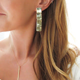 blond woman neck closeup wearing gold brass four square post earrings and 14k gold filled single stroke necklace