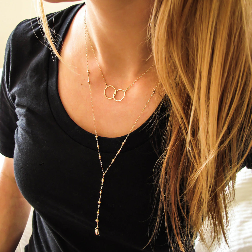 blond woman on a black tshirt wearing a 14k gold filled prism y necklace