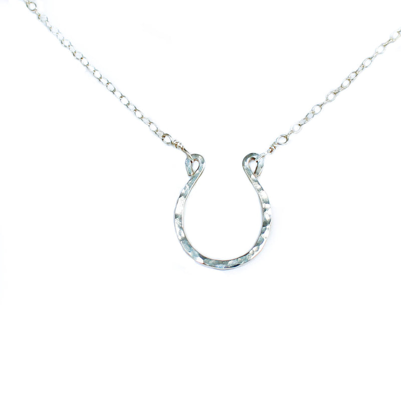 shining horseshoe closeup of a sterling silver good luck horseshoe necklace under a bright light