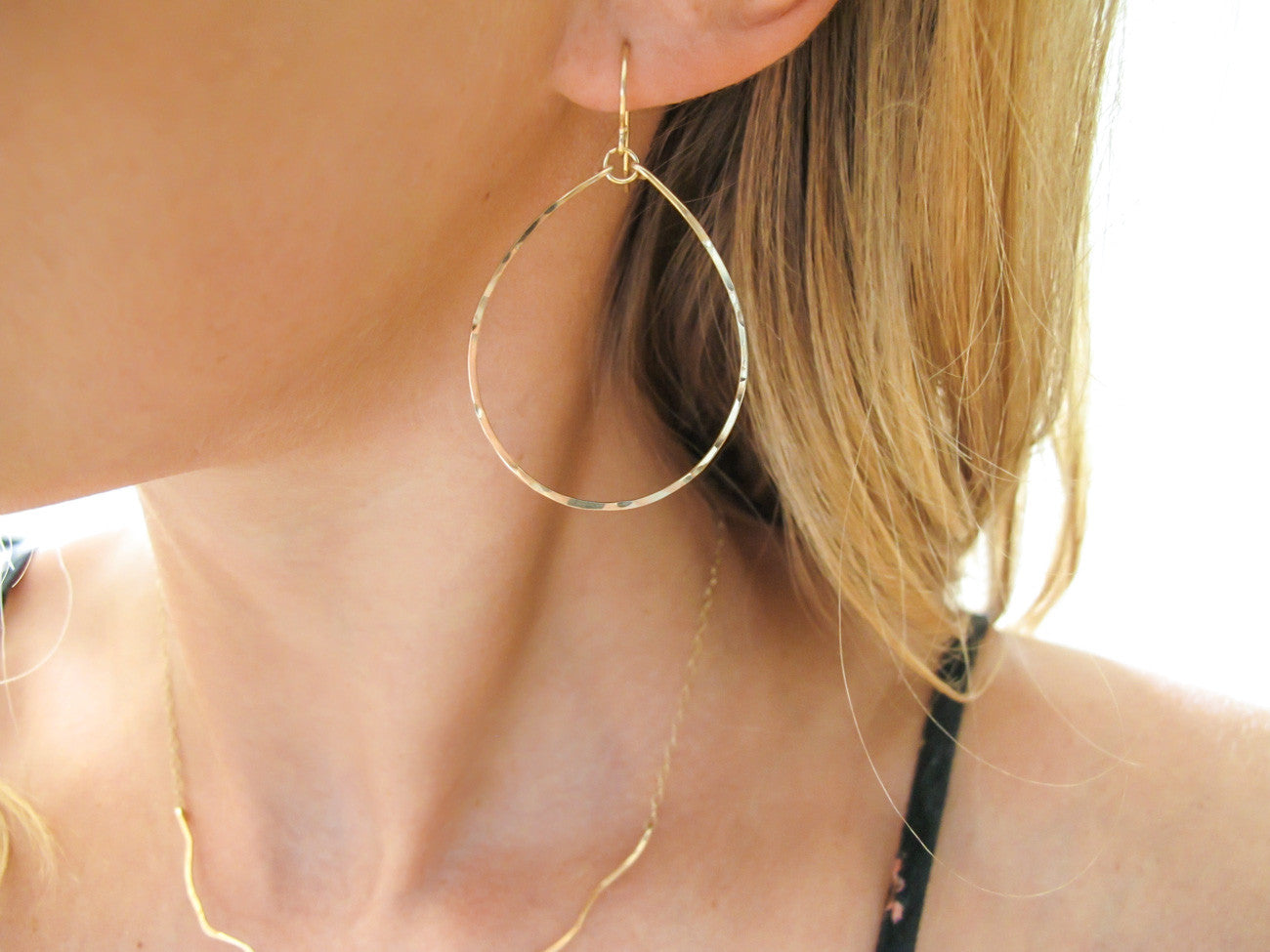 blond woman ear closeup wearing 14k gold filled hoops for nuns hoop earrings