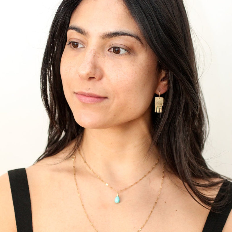 brunette wearing brass jellyfish drop earrings and a 14k gold filled chalcedony gemstone beaded pendant