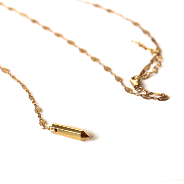 closeup of a 14k gold filled prism y necklace laying on a white surface