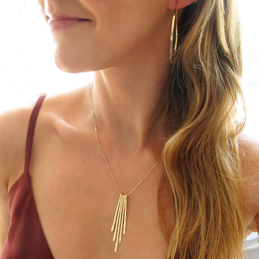 blond woman neck close-up wearing 14k gold filled horizon endless hoop earrings and a 14k gold filled rays pendant