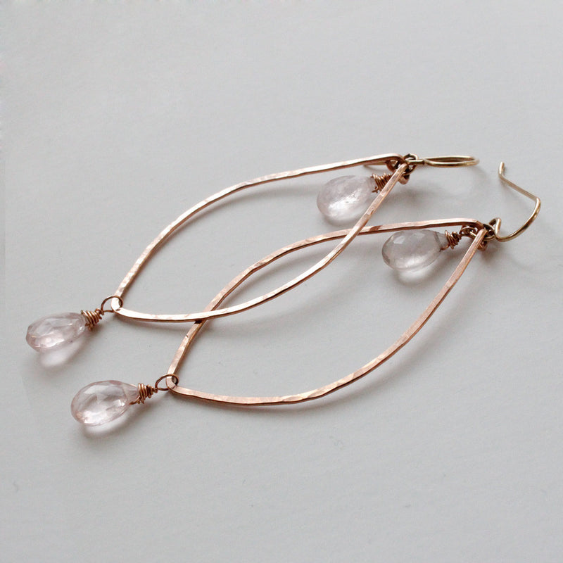 rose quartz rose gold leaf gemstone earrings reflecting light on a gray surface