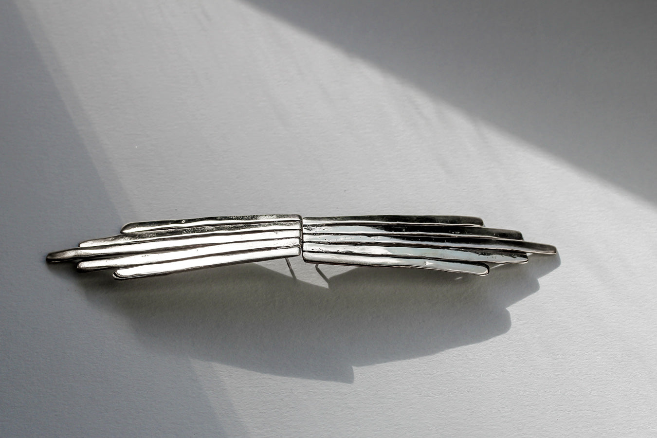 sterling silver empire earrings against each other laying on a grey surface slightly under light