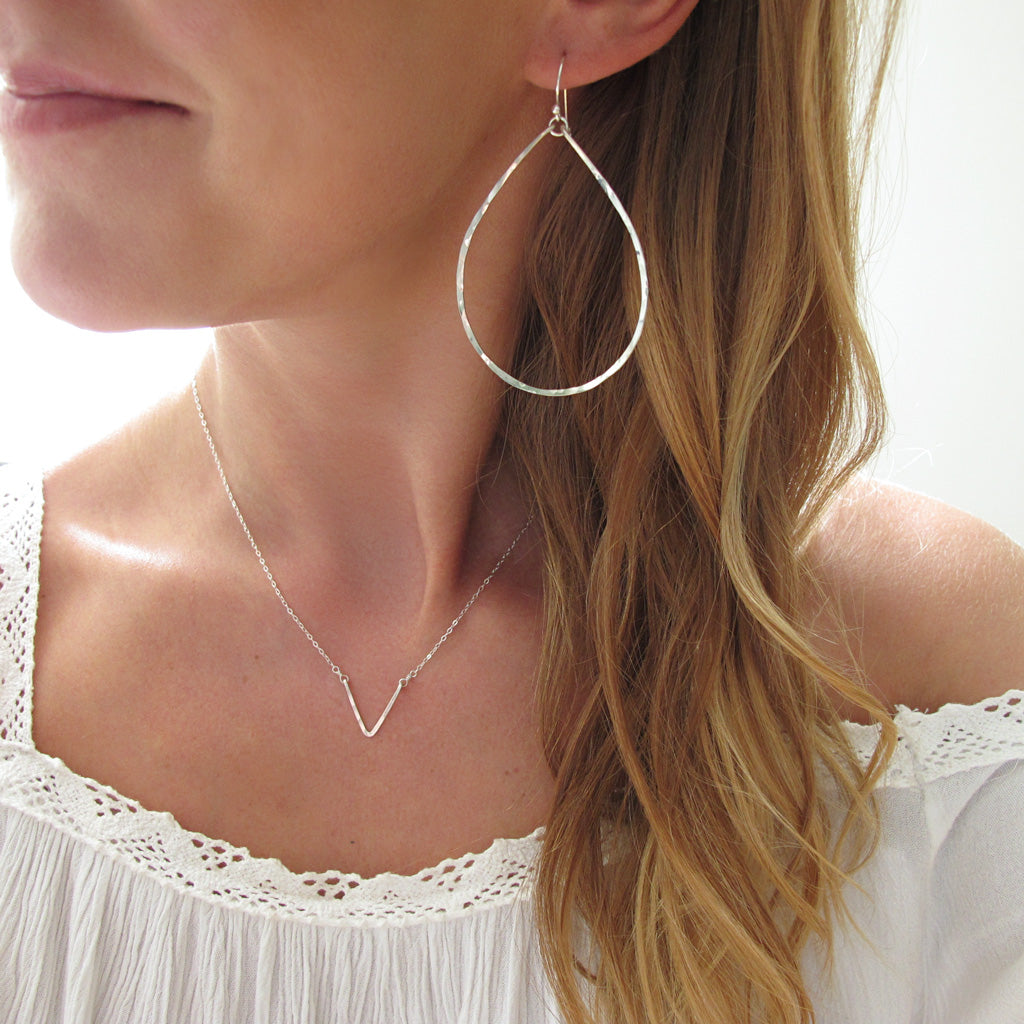 blond woman on a white top wearing sterling silver large teardrop hoop earrings