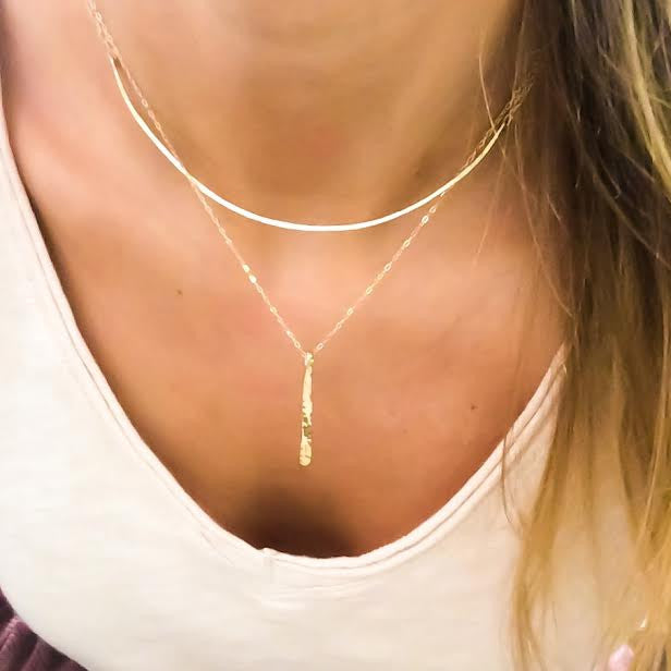 blond woman neck closeup on a white tshirt wearing a 14k gold filled single stroke necklace