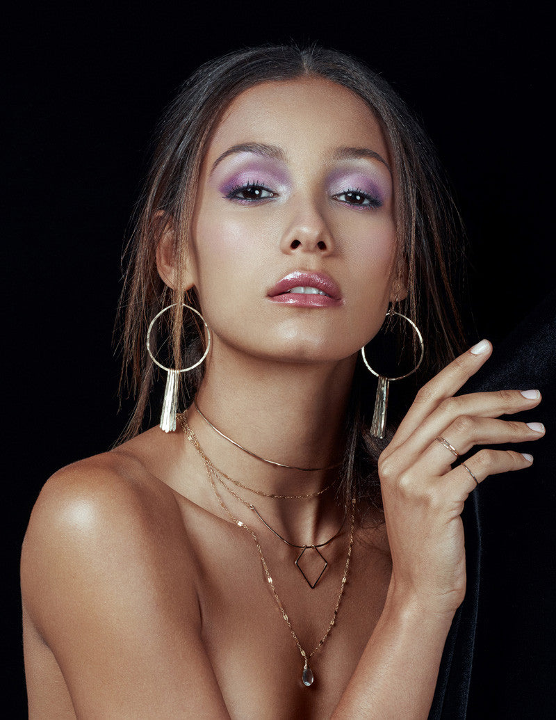 brunette looking at camera wearing 14k gold filled xl round fringe hoops