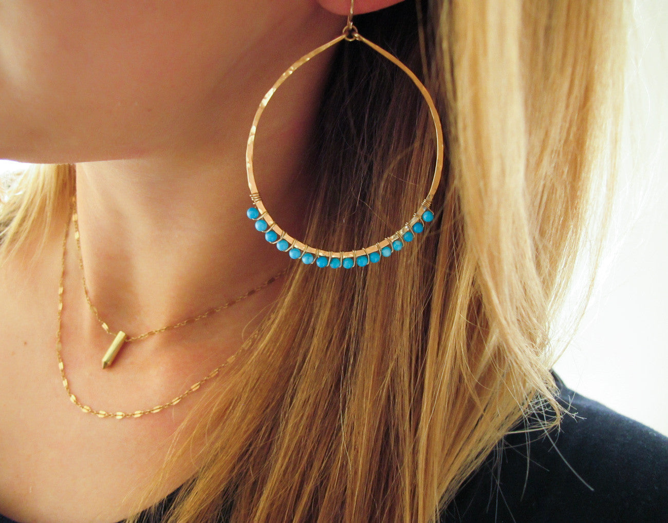 blond woman ear closeup wearing 14k gold filled turquoise xl gemstone arc hoops