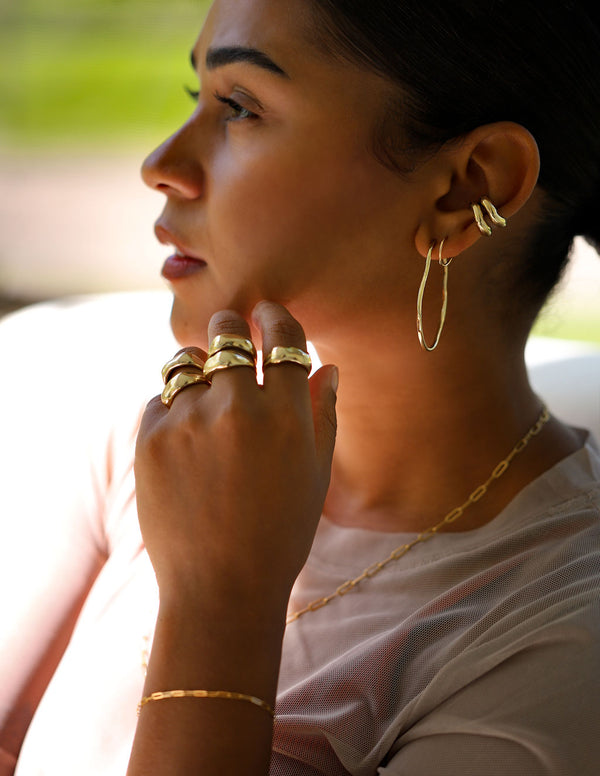 girl with multiple stacked gold rings, hoop earrings and cartilage hug hoops