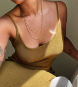 neck down view of woman with two gold chain necklaces wearing a green dress