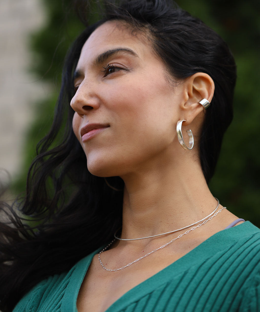 girl with bright silver jewelry wearing green sweater