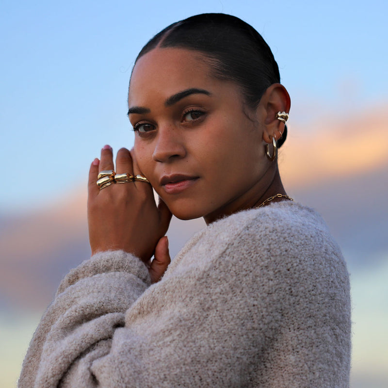 girl with chunky gold jewelry and a cozy sweater outside at dusk