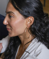 side view of a girl with black curly hair wearing large gold hoops