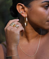 girl with large gold hoops, cartilage earrings and thick rings and a rope chain necklace in gold