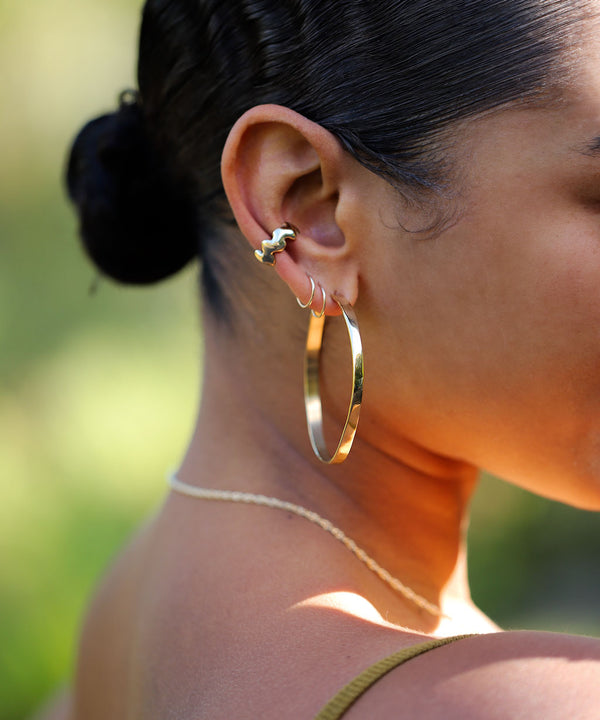 girl with large gold hoops, cartilage earrings and thick rings and a rope chain necklace in gold