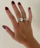 Hand wearing a two silver rings on a plain background