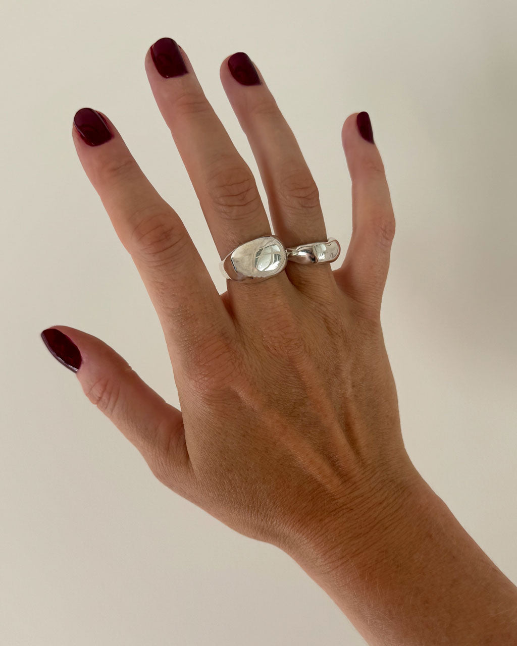hand with 2 silver rings on plain background