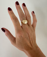 hand with chunky gold ring on plain background