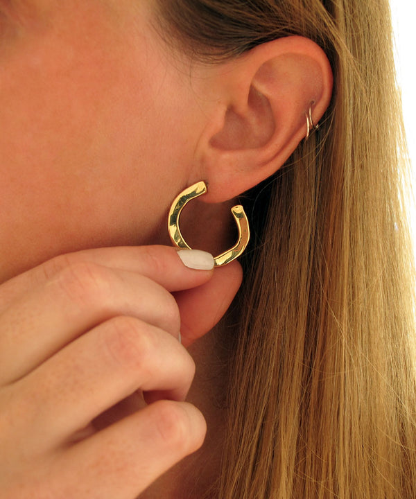 hand holding gold medium hoop earring to the side