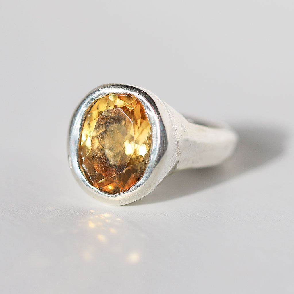 Silver ring with a yellow citrine gemstone on a light gray background