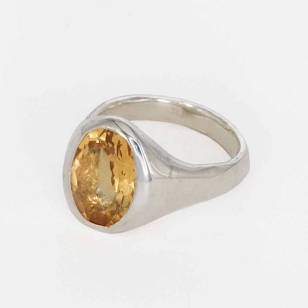 Silver ring with a yellow gemstone on a white background