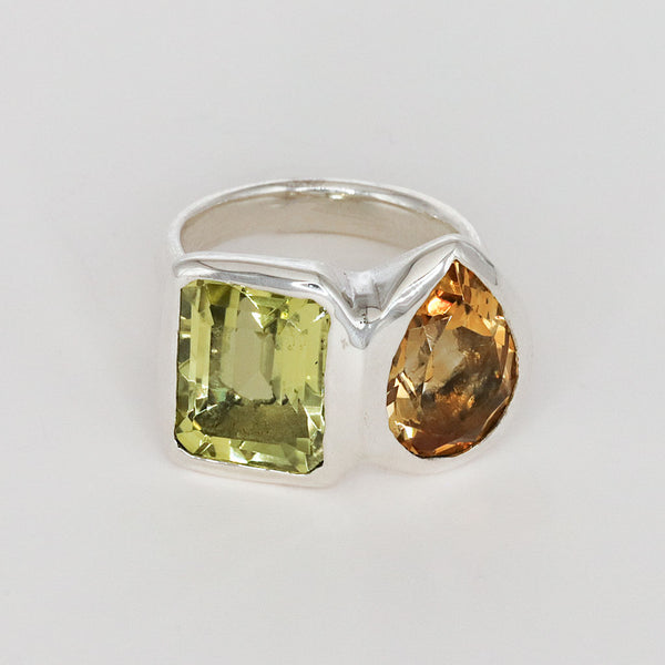 Silver ring with green and orange gemstones on a white background
