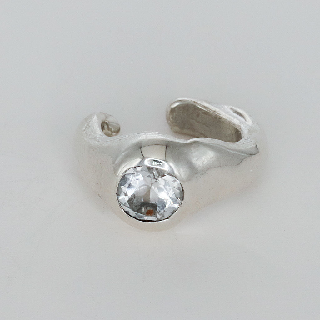 Silver earring with a clear gemstone on a light gray background