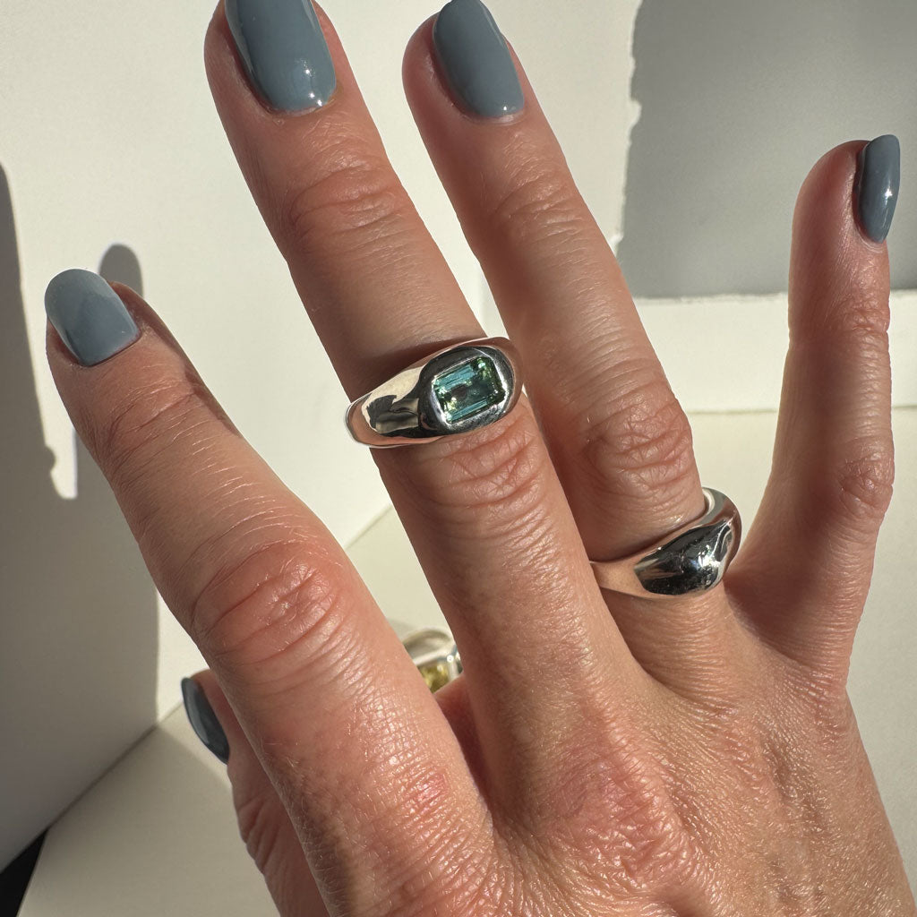Hand with two silver rings on a neutral background