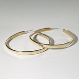 side view of large gold flat hoop earrings