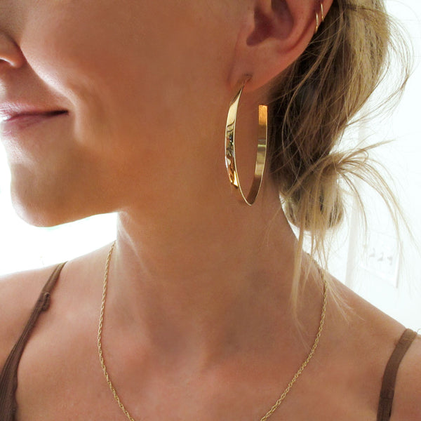 side view of girls face wearing large flat gold hoop earrings