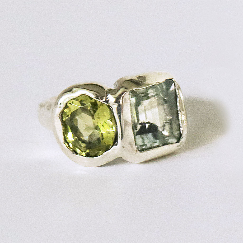 Silver ring with green gemstones on a white background